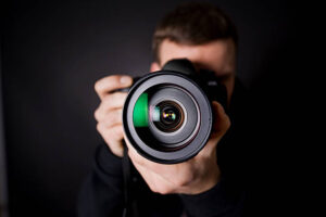 Portrait of a photographer against black wall.